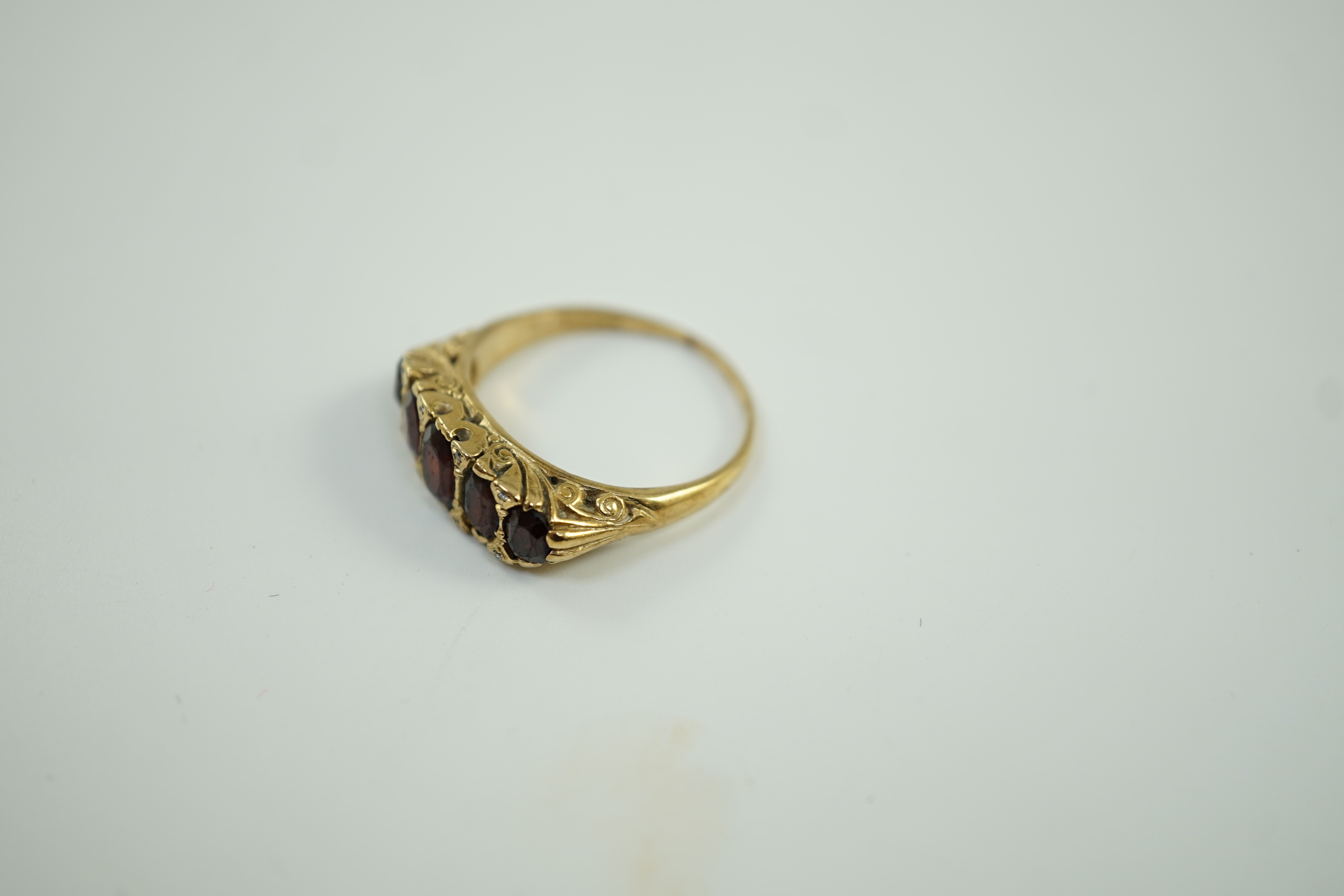 A 1960's Victorian style 9ct gold and graduated five stone garnet set half hoop ring, with diamond chip spacers, size V, gross weight 6 grams.
